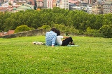 Una coppia contempla una veduta panoramica della città seduta nel parco della collina sopra il centro storico