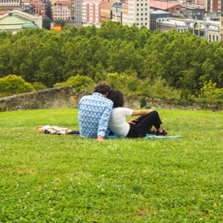 Couple watching a beautiful panoramic view of the city sitting in the park, on the hill above the Old Town