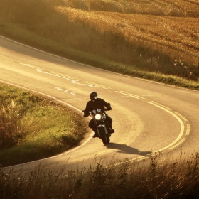 Motociclista che guida lungo una strada Motociclista che guida lungo una strada