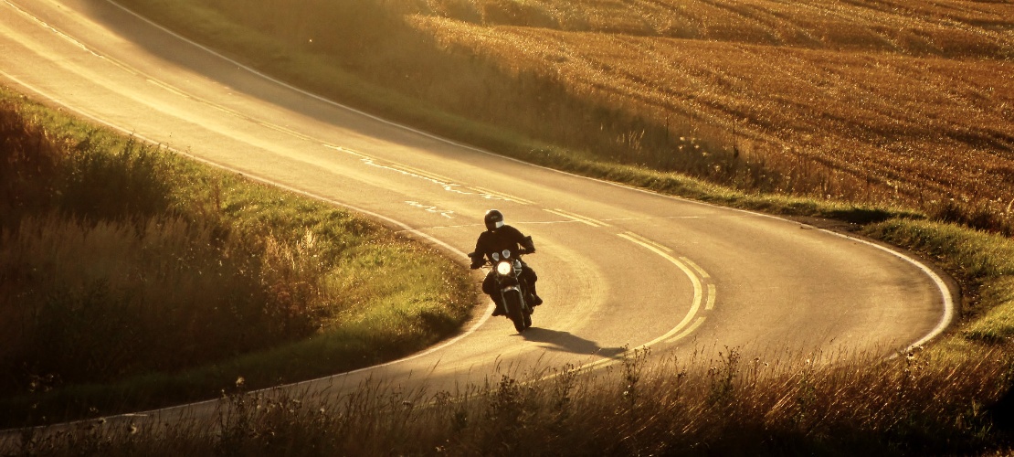 Motociclista che guida lungo una strada