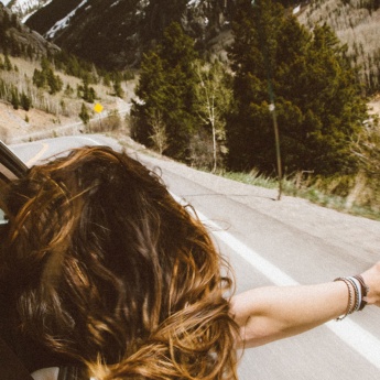 Una ragazza si affaccia dal finestrino di un’auto su una strada di montagna