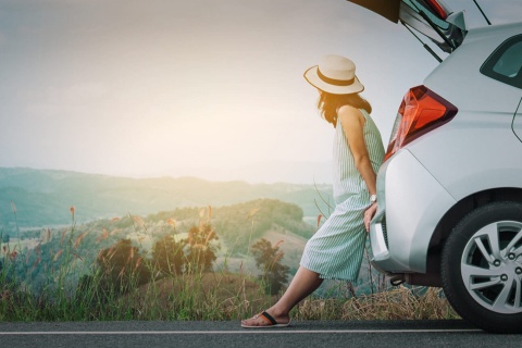 Touristin an ihrem Auto bei einer Pause während einer Rundfahrt