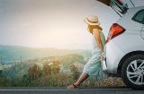 Tourist leaning on their car, resting from their journey by road