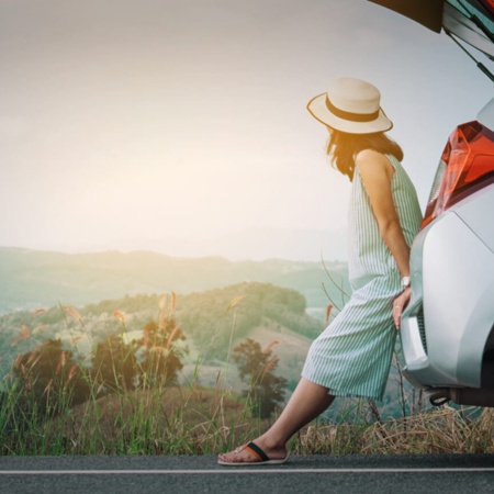 Turista apoyada en el coche descansando de su viaje en carretera