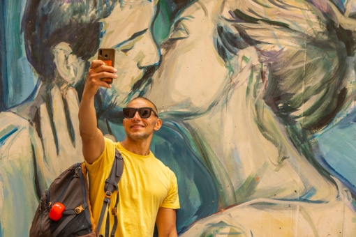 Турист делает селфи на фоне одного из изображений граффити в Валенсии, Валенсийское сообщество