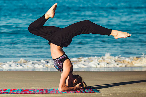 Moça praticando ioga na praia