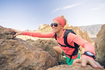 Hiker climbing some rocks in a volcanic landscape