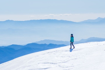 Hiker looking out over snowcapped mountains in Girona, Catalonia