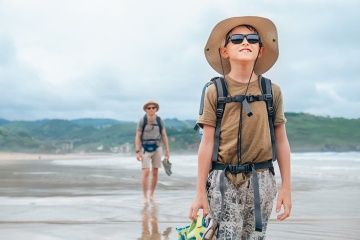  Pielgrzymi przechodzący przez plażę na szlaku Drogi Północnej