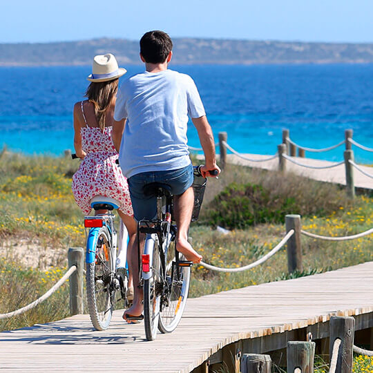 Paar fährt am Strand von Formentera Fahrrad