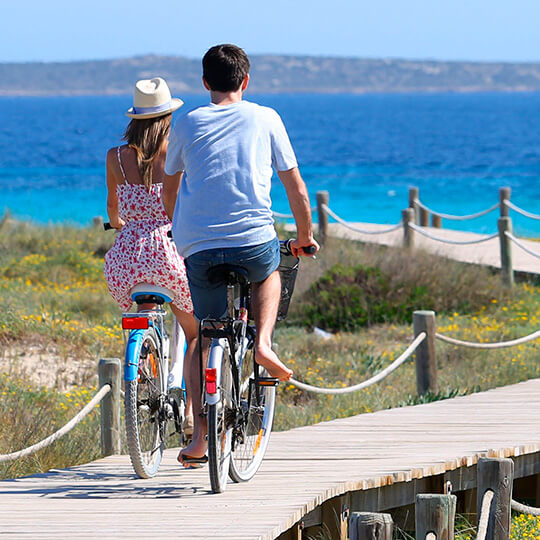 Paar fährt am Strand von Formentera Fahrrad Paar fährt am Strand von Formentera Fahrrad