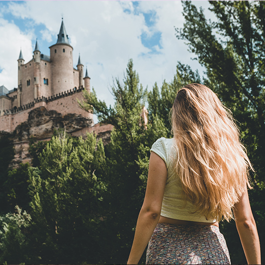 Moça jovem contemplando o Castelo Alcázar de Segóvia