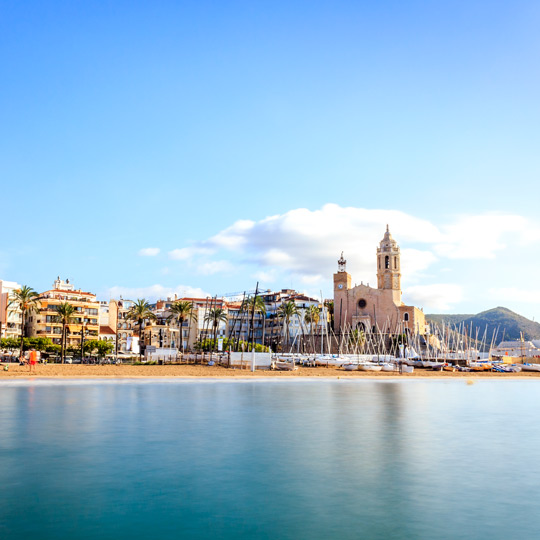 Blick auf den Strand von Sitges und die Kirche von Sant Bartomeu, die sich im Hafen von Sitges befindet