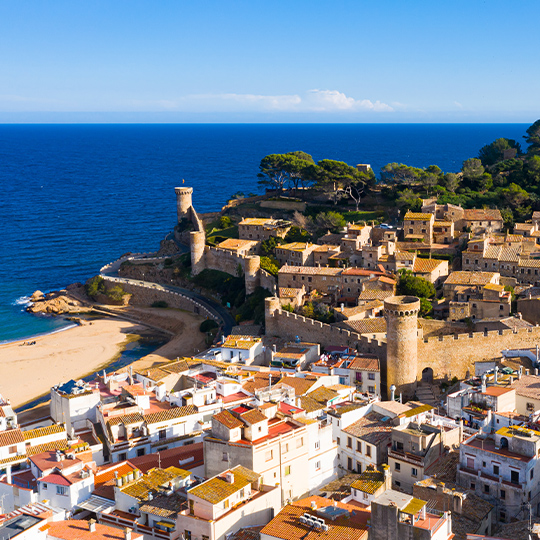 Vista aérea do pequeno povoado de Tossa de Mar, entre o mar e as montanhas de Girona