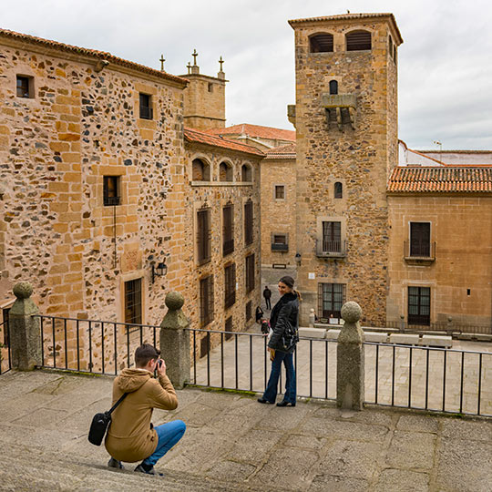 Turyści robiący zdjęcie na placu św. Jerzego z pałacem Golfines de Abajo w tle, Cáceres