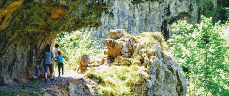 Randonneurs traversant un chemin creusé dans un rocher dans les gorges des Xanas.