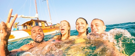 Giovani che nuotano vicino a una barca a vela a Ibiza
