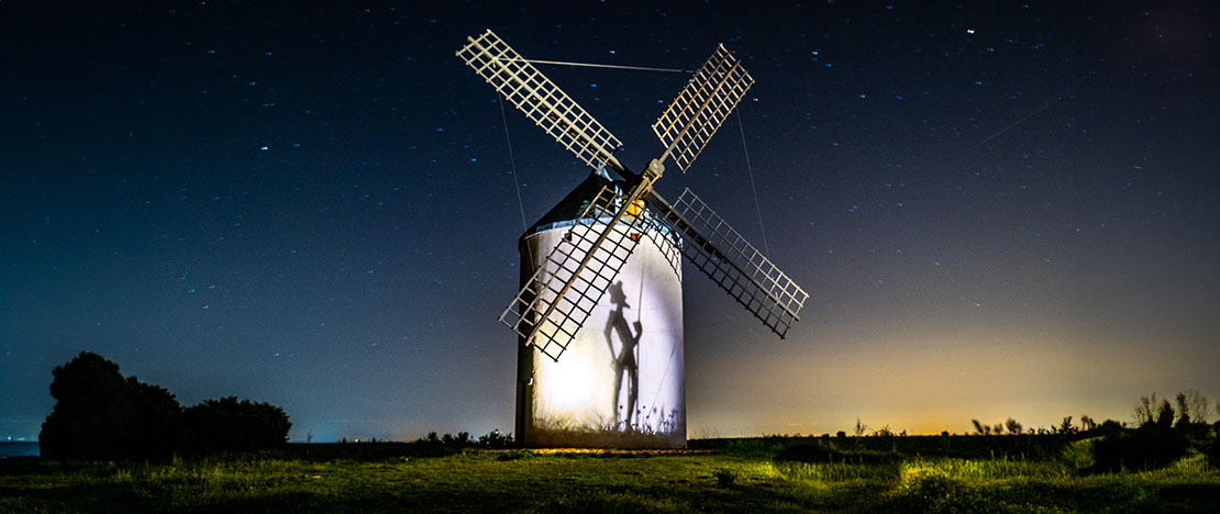 Gwiaździsta noc w Kastylii-La Mancha z cieniem Don Kichota na ścianie wiatraka Gwiaździsta noc w Kastylii-La Mancha z cieniem Don Kichota na ścianie wiatraka