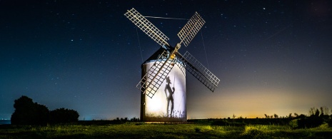Noche estrellada en Castilla-La Mancha con imagen del Quijote reflejada sobre un molino