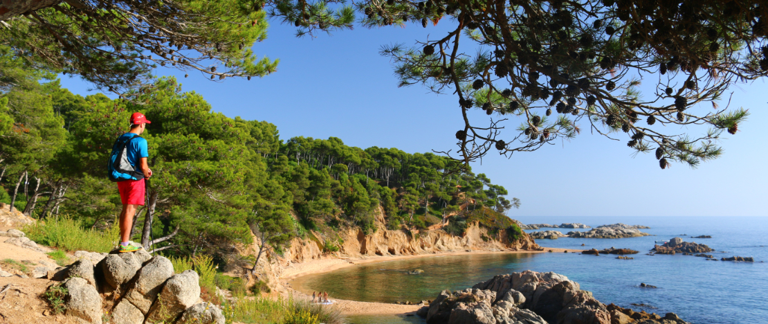Praticante de trekking no Camí de Ronda contemplando a Cala Estreta de Palamós, em Girona, Catalunha Praticante de trekking no Camí de Ronda contemplando a Cala Estreta de Palamós, em Girona, Catalunha