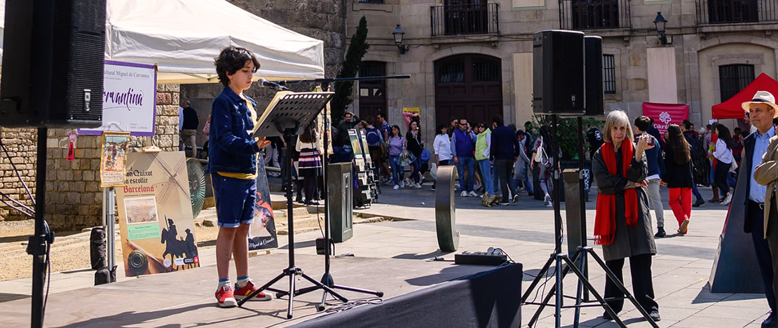 Enfant lisant Don Quichotte devant la cathédrale de Barcelone pendant la Sant Jordi Enfant lisant Don Quichotte devant la cathédrale de Barcelone pendant la Sant Jordi