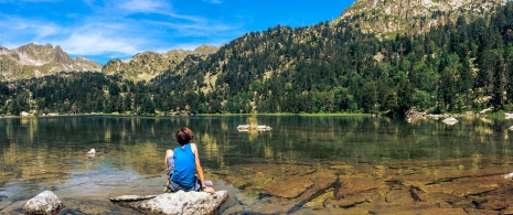 Dziecko siedzące nad jednym z jezior Parku Narodowego Aigüestortes i Estany de Sant Maurici w Lérida, Katalonia