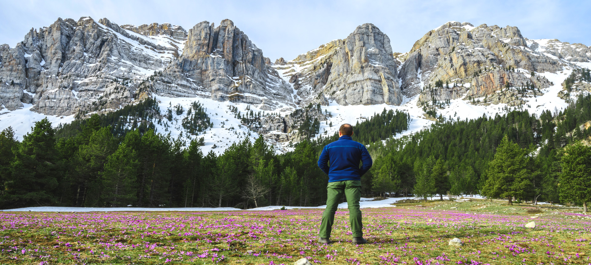 Un turista contempla le splendide montagne innevate in primavera a Prat de Cadi, Catalogna Un turista contempla le splendide montagne innevate in primavera a Prat de Cadi, Catalogna