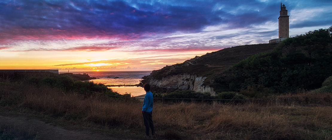 Menina contemplando o pôr do sol perto da Torre de Hércules, Galiza Menina contemplando o pôr do sol perto da Torre de Hércules, Galiza