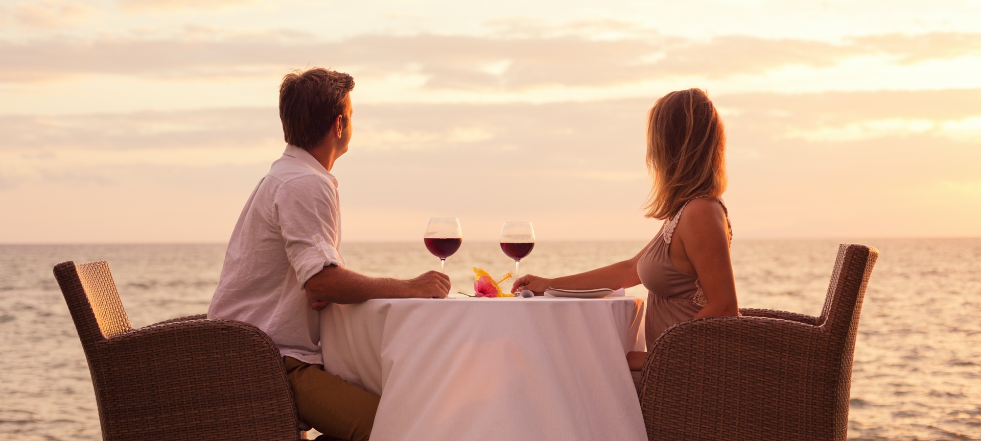Un couple boit un verre de vin face à la mer Un couple boit un verre de vin face à la mer