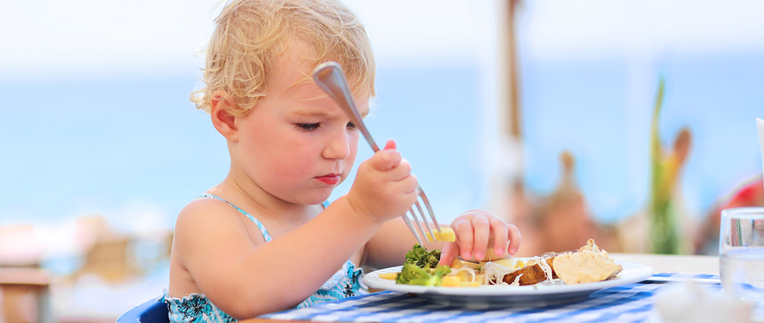 Menina comendo em um restaurante à beira-mar durante as férias. Menina comendo em um restaurante à beira-mar durante as férias.