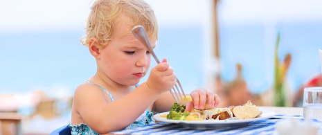 Menina comendo em um restaurante à beira-mar durante as férias. Menina comendo em um restaurante à beira-mar durante as férias.