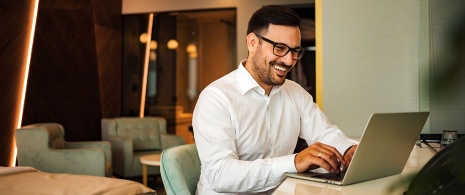 Homem utilizando um computador em seu quarto de hotel