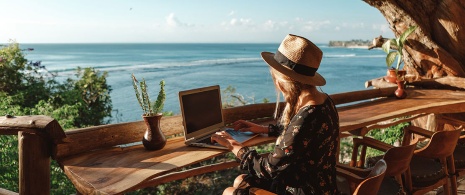 Девушка работает за ноутбуком с видом на море