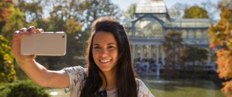 Mulher tirando uma selfie em frente ao Palacio de Cristal, em Madri (Comunidade de Madri)