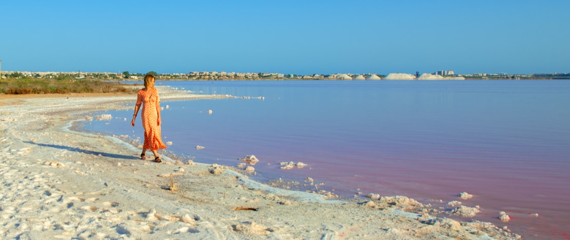 Tourist looking at the pink lagoon of La Mata y Torrevieja in Alicante, region of Valencia Tourist looking at the pink lagoon of La Mata y Torrevieja in Alicante, region of Valencia