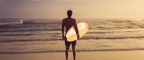 Surfer betrachtet die Wellen vom Strand aus